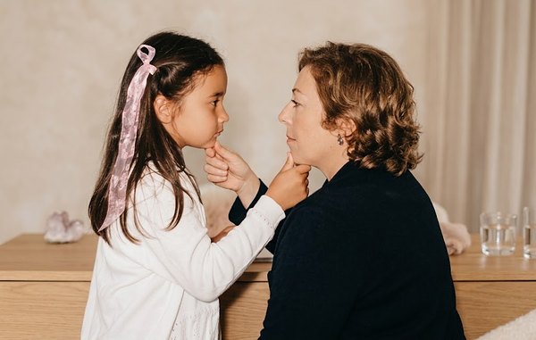 Souvenir : Luisa, il y a une vingtaine d'années, face à une petite fille ; chacune tient doucement le menton de l'autre